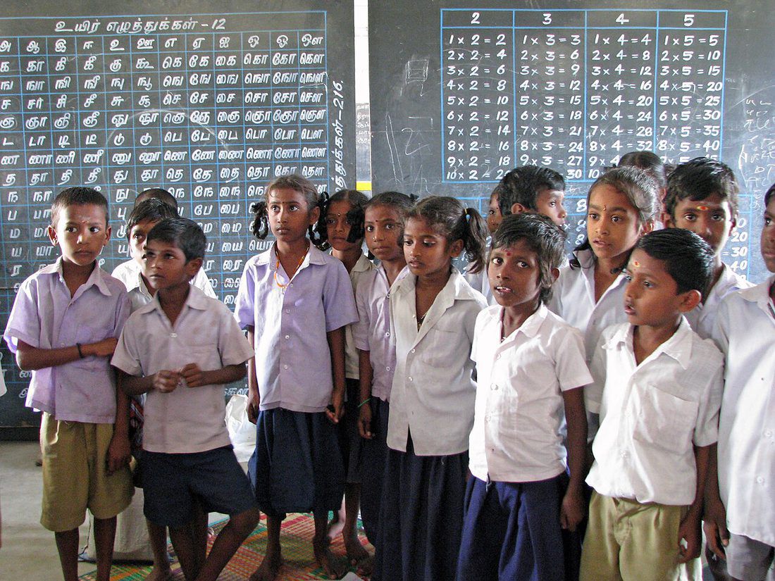 School children standing in a classroom in front of a blackboard